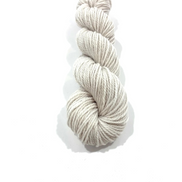 A single skein of twisted yarn in a light oatmeal beige color, photographed vertically against a clean white background with a soft drop shadow.
