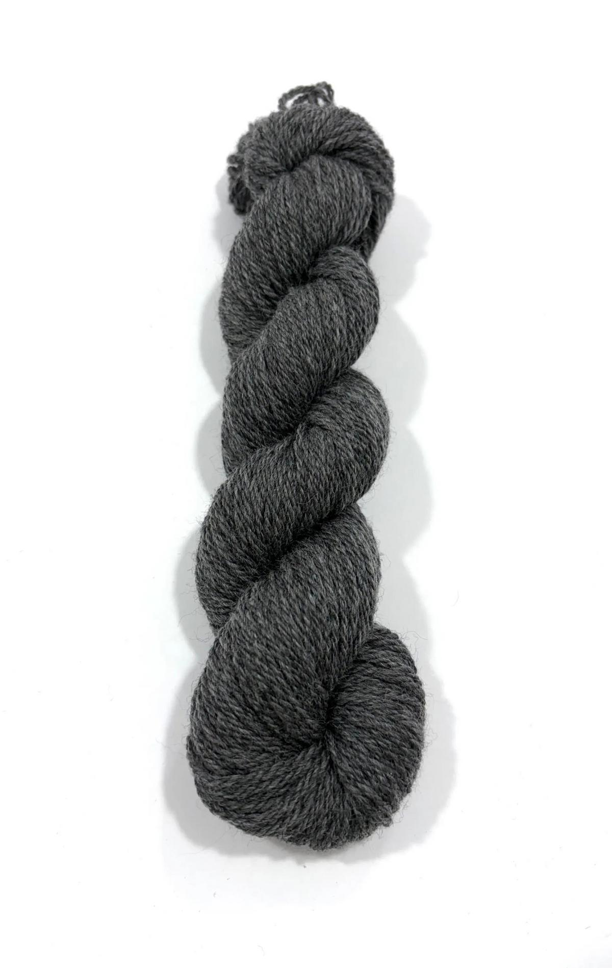 A single skein of dark charcoal gray heathered yarn, twisted into a braid, photographed on a clean white background with a soft drop shadow.