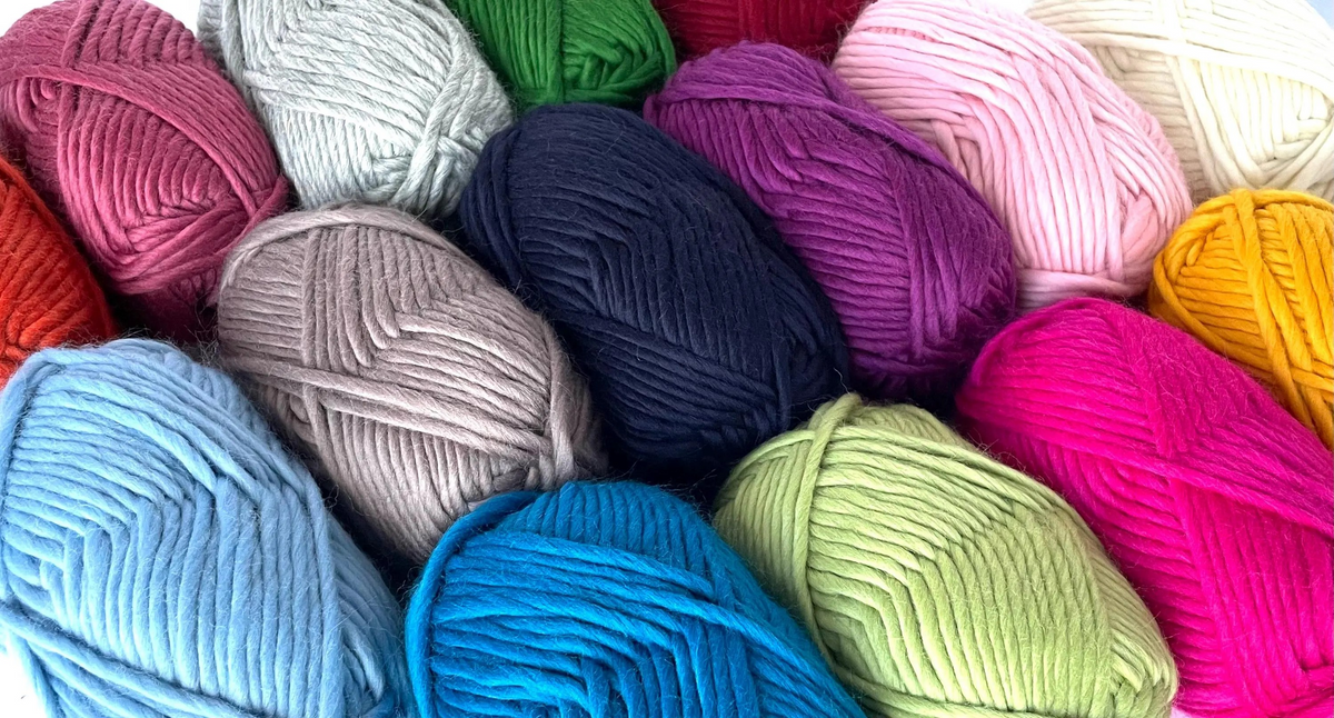 Bulky Weight Yarn 100% Merino Wool Super Bulky Yarn Weight 6 Chunky Natural Wool Yarn for Knitting & Crochet Quick Project Yarn. A close-up arrangement of multiple skeins of yarn in assorted colors, including pink, blue, green, purple, beige, orange, and white, filling the frame.