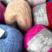 A close-up pile of colorful yarn balls with gray Gepard Kils Silk 5 labels, including pink, blue, beige, red, green, and lavender shades.