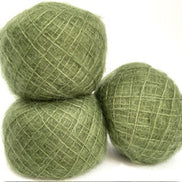 Three balls of textured sage green yarn stacked together on a plain white background.
