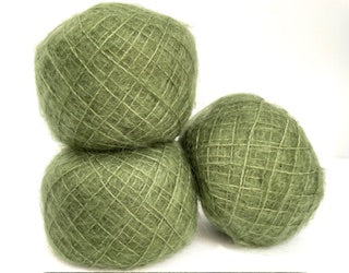 Three balls of textured sage green yarn stacked together on a plain white background.
