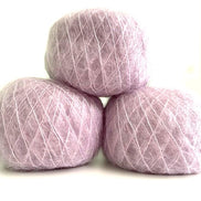 Three balls of fuzzy lavender-pink yarn stacked in a pyramid arrangement on a white background.