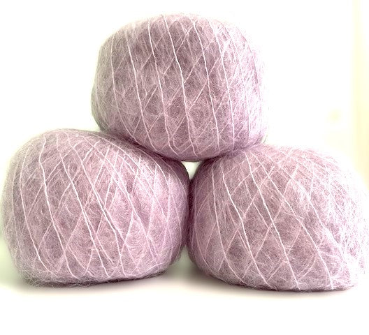 Three balls of fuzzy lavender-pink yarn stacked in a pyramid arrangement on a white background.
