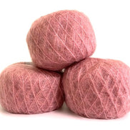 Three balls of dusty rose pink yarn stacked in a pyramid on a white background.