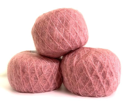 Three balls of dusty rose pink yarn stacked in a pyramid on a white background.