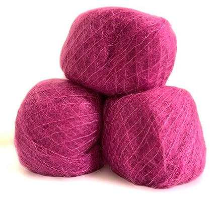 Three balls of magenta pink yarn stacked together on a white background.