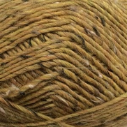 A close-up of variegated yarn in a warm mustard yellow, golden brown, and tan colorway with subtle dark flecks.
