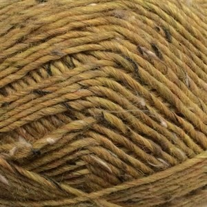 A close-up of variegated yarn in a warm mustard yellow, golden brown, and tan colorway with subtle dark flecks.