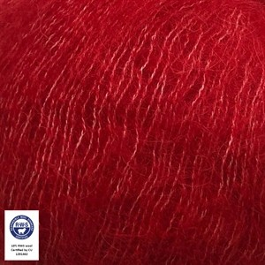 A close-up of bright red yarn texture with a small white certification label in the bottom-left corner.
