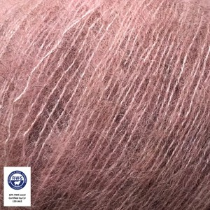 A close-up of dusty rose pink mohair yarn strands, showing its soft, fuzzy texture. A small white circular certification logo is visible in the bottom-left corner.