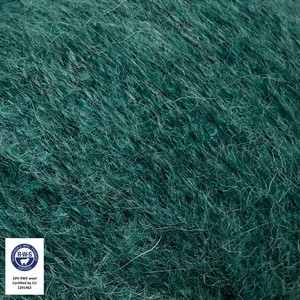 A close-up texture shot of dark teal green mohair yarn, showing the fine, fluffy fibers. A small white certification label is visible in the bottom-left corner.