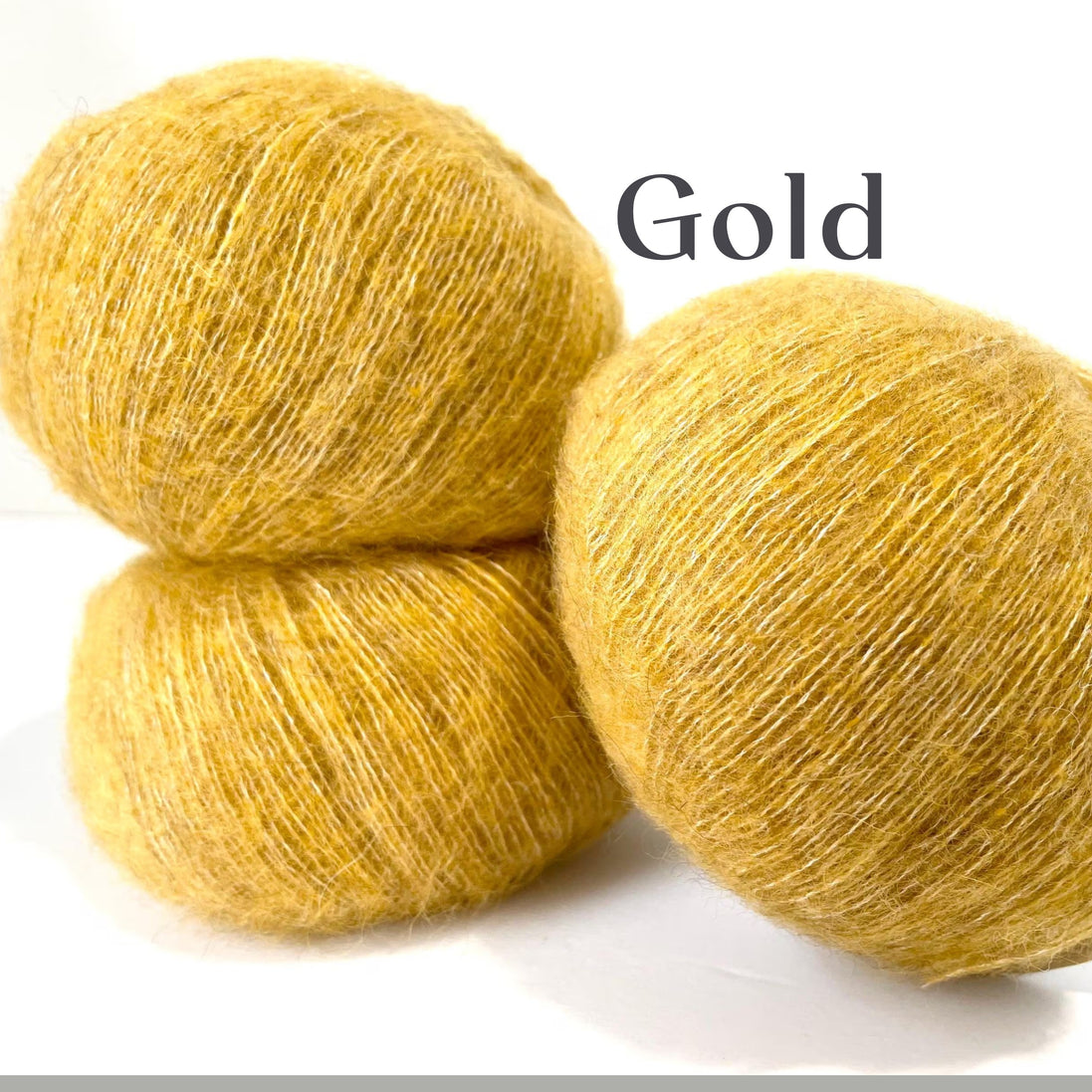 Three balls of fuzzy yarn in a warm golden yellow color, stacked on a white background with the word 'Gold' printed in black text.