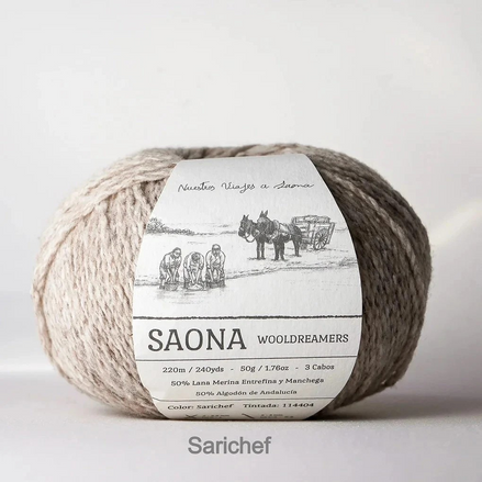 A ball of natural beige wool yarn with a white paper label reading 'SAONA WOOLDREAMERS' and 'Nuevos Vinajes a Saona,' photographed against a plain light background. A faint 'Sarichef' watermark appears below the product.