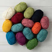Bulky Weight Yarn 100% Merino Wool Super Bulky Yarn Weight 6 Chunky Natural Wool Yarn for Knitting & Crochet Quick Project Yarn. A collection of colorful yarn skeins arranged in a circle on a white wooden surface. The yarns come in a variety of colors including cream, olive green, navy, mustard yellow, teal, pink, orange, purple, and forest green.